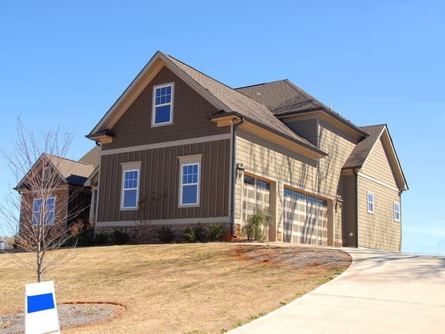 Two-story home with a for-sale sign in the front yard
